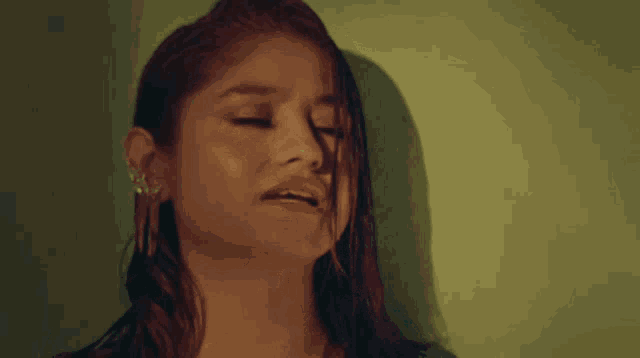 a close up of a woman 's face with her eyes closed and a green background