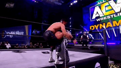a man is wrestling in a wrestling ring with a sign that says aew wrestling on it .