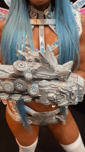 a woman with blue hair is holding a silver object in her hand