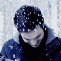 a close up of a man 's face with snow falling on it .