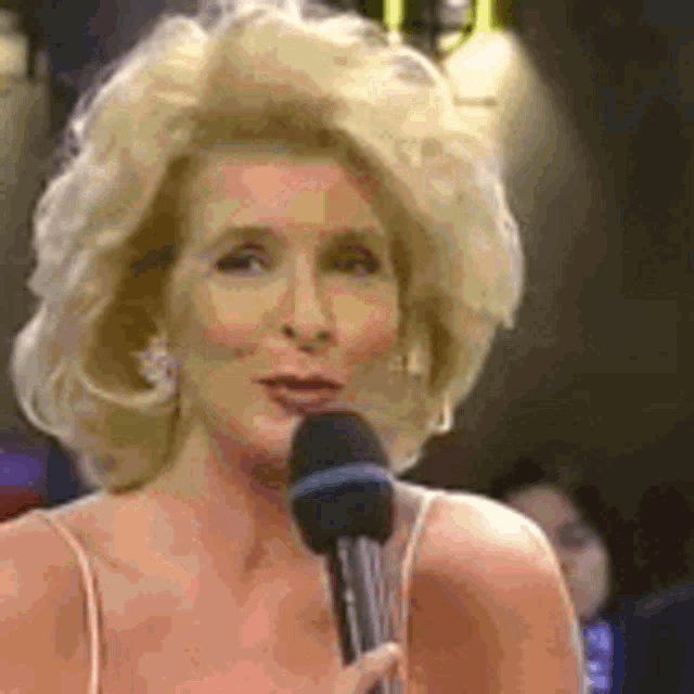 a woman is holding a microphone in front of her face and smiling .