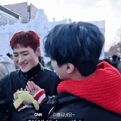 a man in a red scarf holds a stuffed animal with the word onn written on it