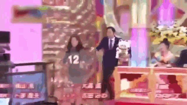 a woman wearing a number 12 shirt is dancing on a stage .