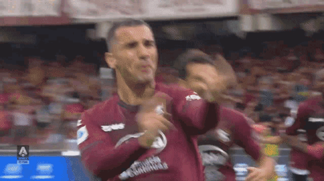 a soccer player in a maroon jersey with the letter a on the front