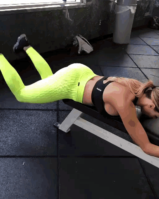 a woman is laying on a bench in a gym wearing reebok