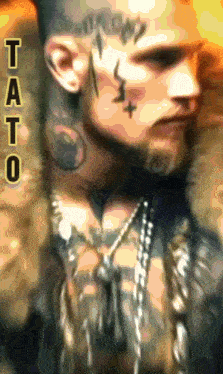 a man with a tattoo on his face has the word tato on the bottom right