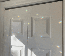 a white door with a rainbow of light coming through it