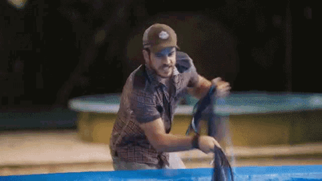 a man is standing next to a pool holding a dolphin .