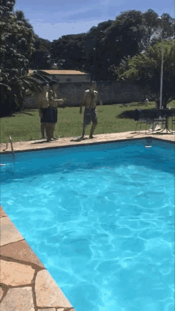 two men are standing on the edge of a swimming pool looking at something