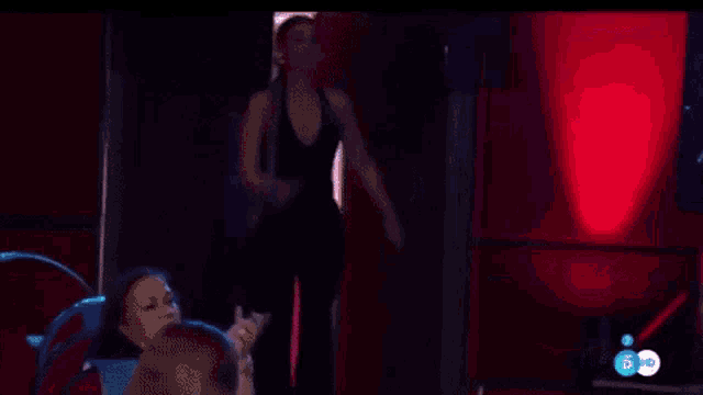 a woman in a black dress is dancing in front of a red background