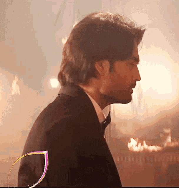 a man in a tuxedo and bow tie is standing in front of a fire