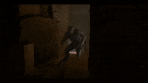 a person walking through a dark cave with a light shining on them