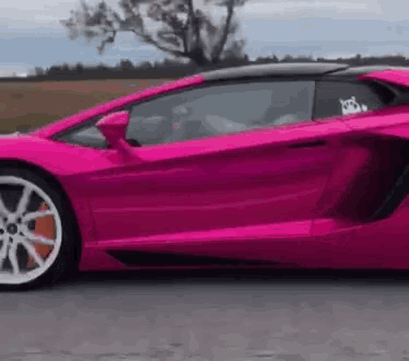 a pink lamborghini aventador is driving down a road .
