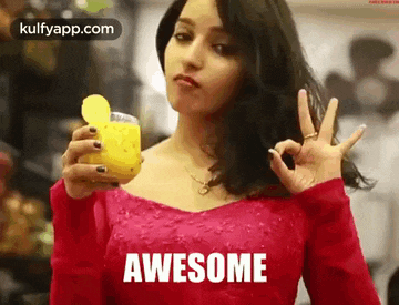 a woman in a red dress is holding a glass of lemon juice and giving an ok sign .