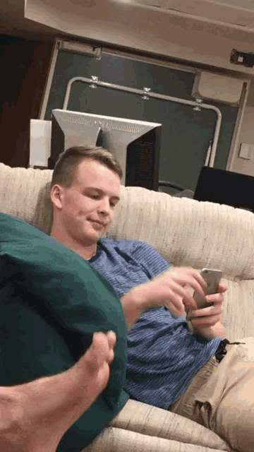a man is laying on a couch looking at his phone