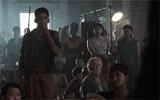 a man is standing in front of a crowd of people in a dark room .