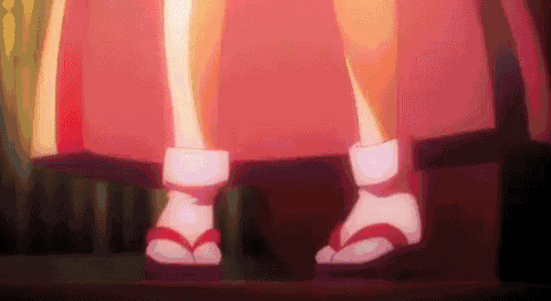 a close up of a person 's feet wearing flip flops and a red skirt .