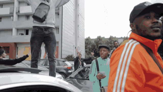 a man in an orange adidas jacket stands in front of a crowd