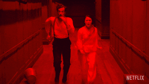 a man and a woman are running in a dark room with netflix written on the bottom right