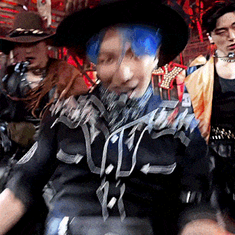 a man with blue hair and a cowboy hat is dancing