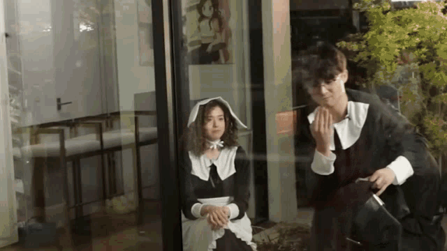 a man and a woman dressed in costumes are looking out a window