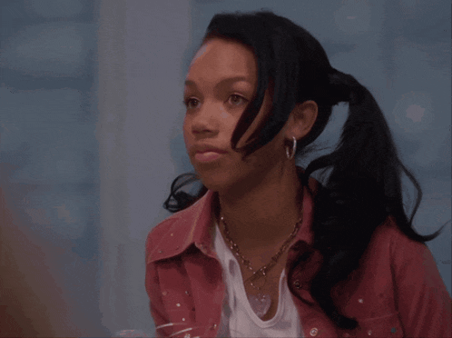 a girl with a ponytail wearing earrings and a pink shirt