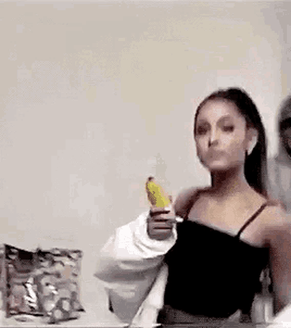 ariana grande is holding a banana like a gun .