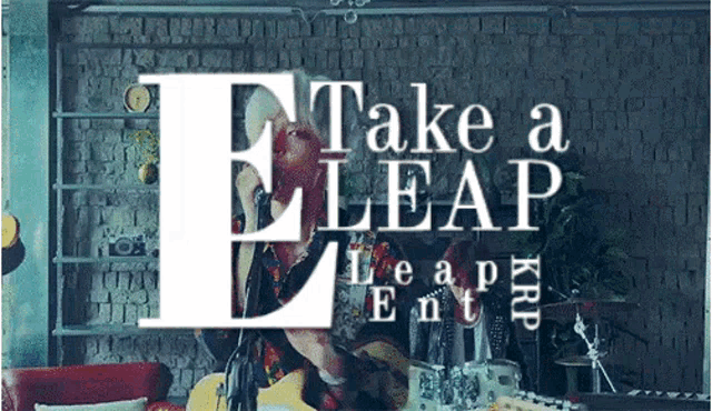 a man playing a guitar in front of a sign that says take a leap kid