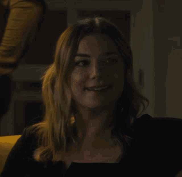 a woman in a black top is smiling and looking to the side