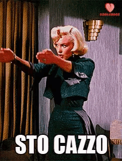 a woman is standing in front of a curtain with the words sto cazzo written on the bottom