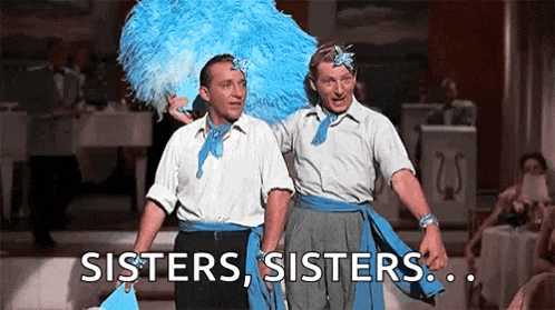 two men are standing next to each other on a stage and one of them is wearing a blue feathered headpiece .