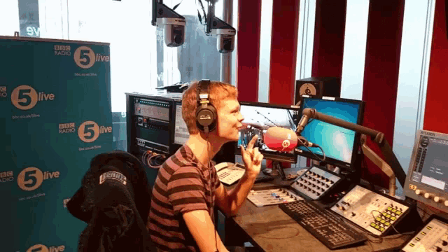 a man sitting in front of a bbc radio 5 live banner