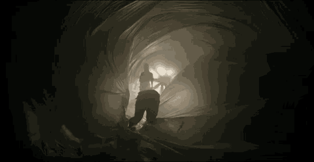 a man is walking through a dark tunnel with a large piece of cloth covering him .
