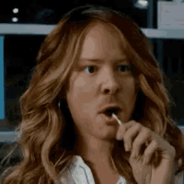 a woman is holding a lollipop in her mouth .