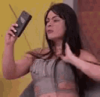 a woman is holding a cell phone in her hand and taking a picture of herself .