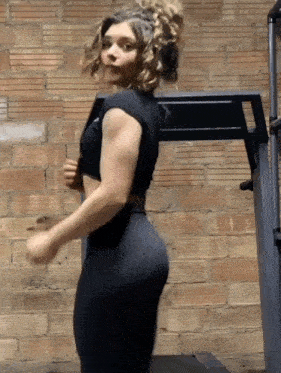 a woman is running on a treadmill with a brick wall in the background .
