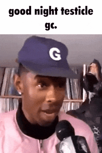 a man in a baseball cap is talking into a microphone .