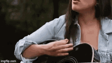 a woman is holding a guitar in her hands and singing .
