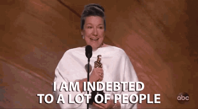 a woman holding a trophy says " i am indeeded to a lot of people "