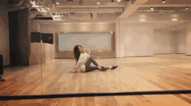 a woman is sitting on the floor in front of a large mirror
