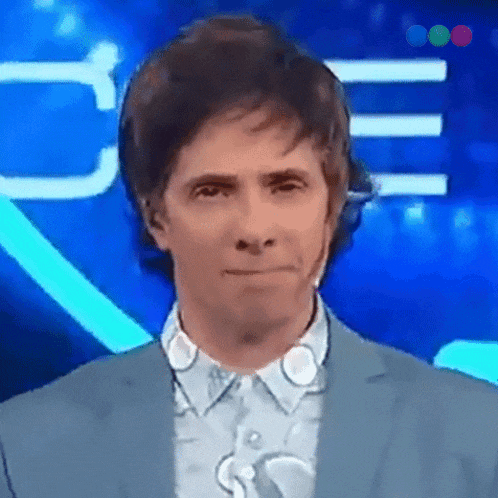 a man in a suit is making a face in front of a blue background