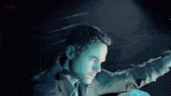a man is standing in a dark room with his arms outstretched and looking at something .