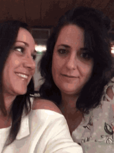 two women are posing for a picture and one has a white shirt on