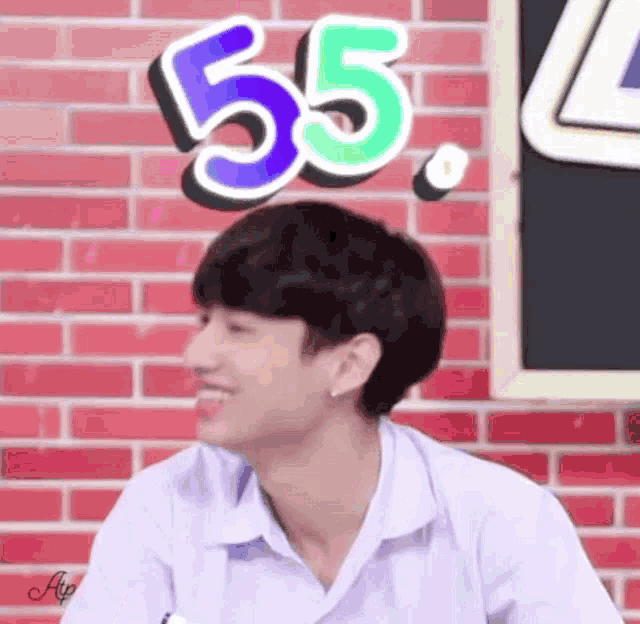 a boy in a white shirt is smiling in front of a sign that says 55