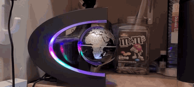 a bottle of m & m 's sits on a desk next to a globe