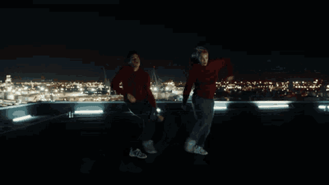 a blurry picture of two people dancing on a rooftop at night