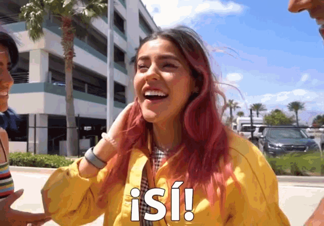 a woman with pink hair and a yellow jacket is laughing and says isi