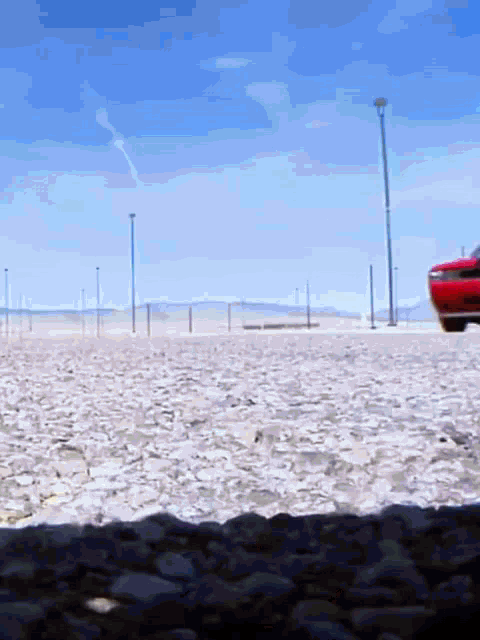 a red car is parked in the middle of a desert
