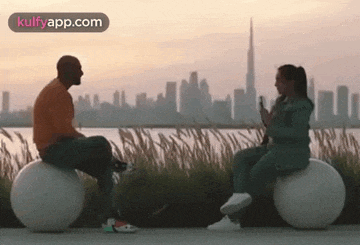 a man and a woman are sitting on balls looking at each other .