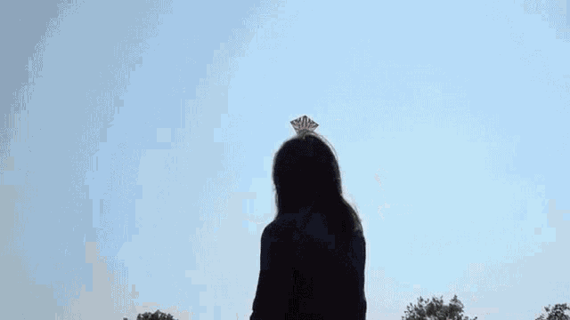 a woman wearing a mask is flying a kite in the sky
